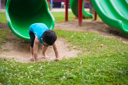 Asian kid playing slide at the playground under the sunlight in summer, Happy kid in kindergarten or preschool school yard.の写真素材