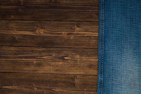 Frayed jeans or blue jeans denim collection on rough dark wooden table background, top view with copy space, old fashion style concept.の写真素材