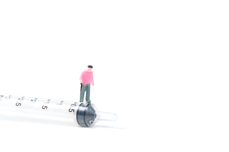 Miniature people, small figure old man or patient with a big syringe, isolated on white background, health care and healthy concept.の写真素材