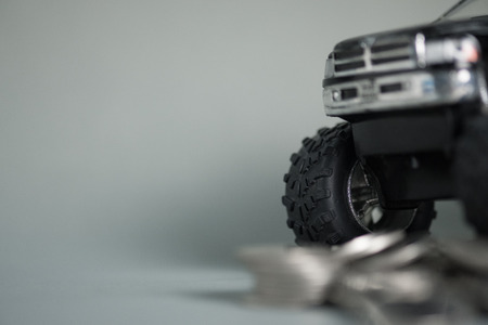 Close up of tire of miniature car pickup truck on stacks of coins with copy space, banking savings...