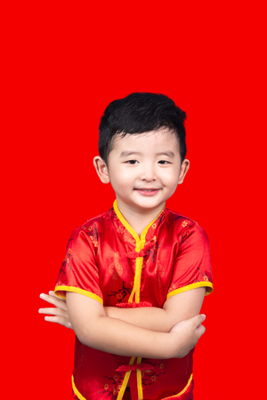 Chinese New Year Concept, Cute Asian boy in red traditional Chinese suit isolated on red background with clipping path.の写真素材