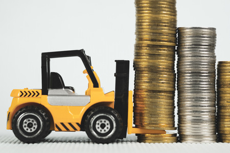 Mini forklift truck with coin stack, business finance and banking industrial concept idea.