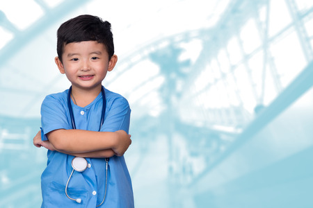 Smiling Asian kid in blue medical uniform holding stethoscope looking at camera, healthy concept idea.の写真素材