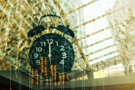 Double exposure of coins stack with alarm clock background and finance graph for business and...