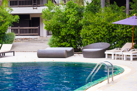 Deck chair or sunbath near private swimming pool with sun umbrella and exotic plants garden, vacation and holiday travel concept.のeditorial素材