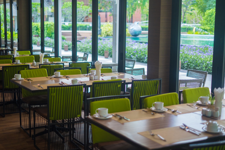 Empty restaurant part of hotel resort with table and armchair near windows and garden view.の写真素材