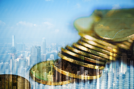 Double exposure of coin stack with financial graph over city and office building background, business and financial concept idea.の写真素材