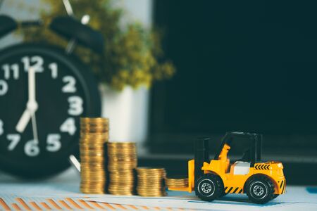 Miniature mini forklift truck with coin stack on working table with office supplies or office work essential tools items for business financial conceptの写真素材