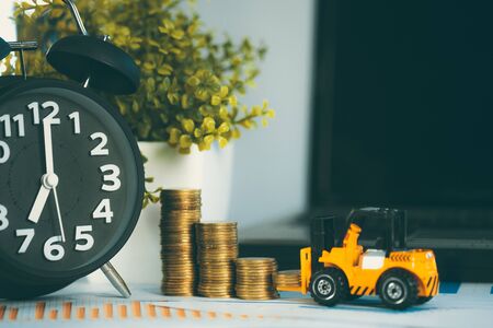 Miniature mini forklift truck with coin stack on working table with office supplies or office work essential tools items for business financial conceptの写真素材