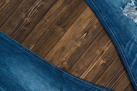 Frayed jeans or blue jeans denim collection on rough dark wooden table background, top view with copy space, old fashion style concept.の写真素材