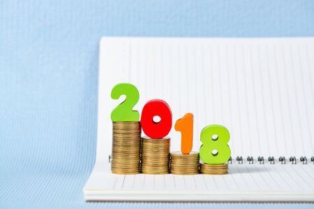2018 wooden text and step of coins stack on notebook paper with copy space for add text, financial...