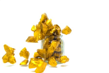 Falling gold nuggets, gold ore , precious stone or lump of golden stone and glass jar isolated on white background.の写真素材