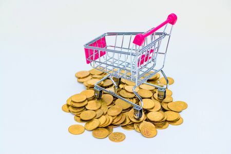 Stack of coins and shopping cart or supermarket trolley on white background, business finance shopping concept.の写真素材