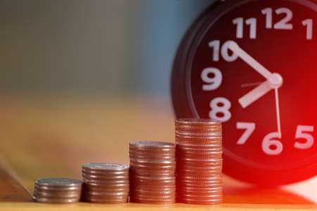 Alarm clock and step of coins stacks on working table, time for savings money concept, banking and business idea. soft tone.の写真素材