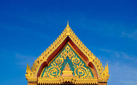 Gold color roof of buddhist temple with blue sky background. isosceles triangle shape.の写真素材