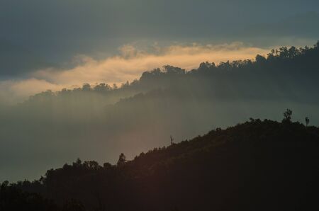A view from mountains to the valley with light and fogの写真素材