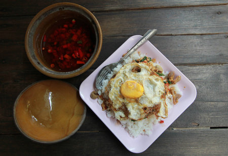 fried basil leaf with chicken and fried eggs on rice in wooden backgroundの写真素材
