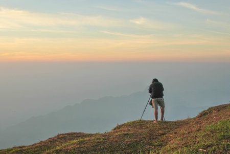 Professional on cliff. Nature photographer takes photos . Dreamy fogy landscape,  winter blue orange...
