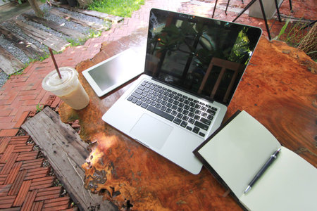 laptop tablet notebook and pensil on Vintage Wooden teble in garden coffee shop