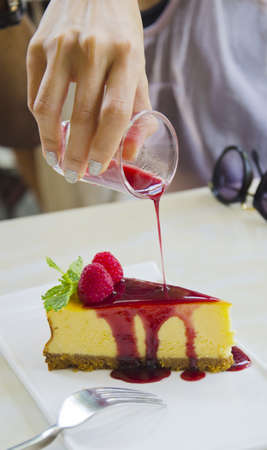 hand of a girl pouring a syrup on the cakeの写真素材