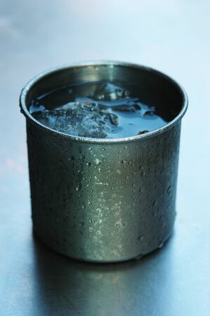 water drops on stainless steal cup with water and ice on a metalic backgroundの写真素材