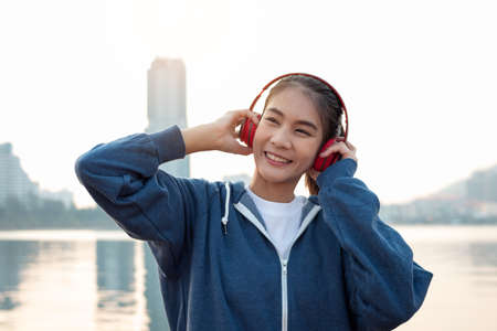 Young woman listening to music with headphones during exercise in the morning.