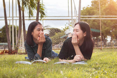 Happy students is reading book on lawn.