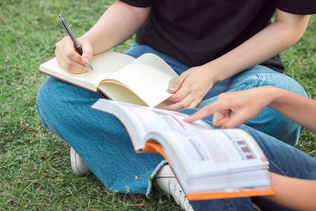 Close up students hand is reading book on lawn.の写真素材