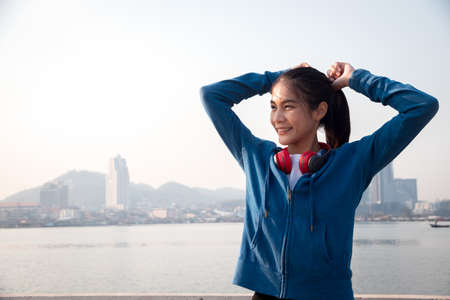 Young woman tying hair getting ready for exercising. Runner woman preparing to run in the city.