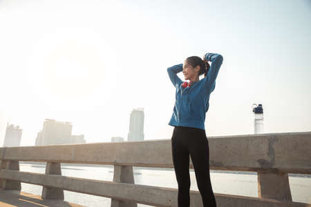 Young woman tying hair getting ready for exercising. Runner woman preparing for run in the city.