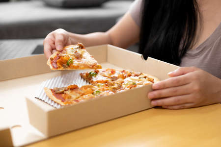 Close up woman hand eating pizzaの写真素材