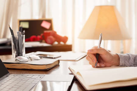 Close up woman hand working at home. Hand of freelancer writing note for work. work at home concept.