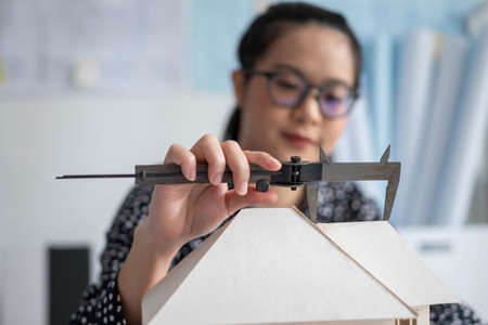 Engineer using Vernier caliper to measuring architectural model.
