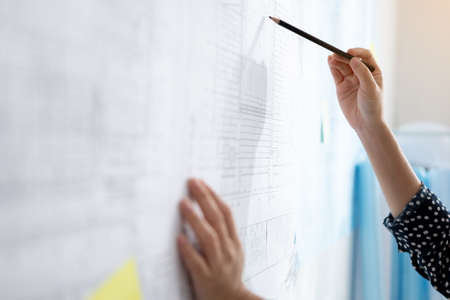 Close up woman hand is writing note paper work on wall.
