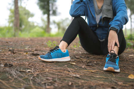 Women is taking a break after running in the morning. Tired female is resting in forest.