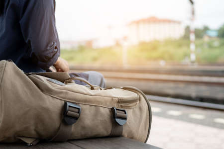 Close up backpack at train station with a traveler. Traveler is waiting for train at the railway station.の写真素材