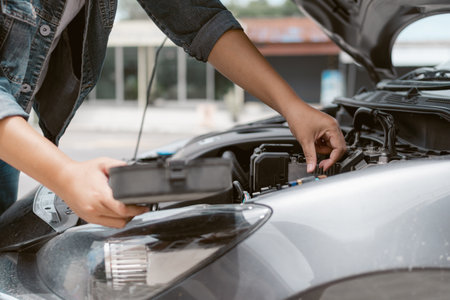 Hand male is checking inside car bonnet after car breakdown. Close up hand is trying to repair a car engine.の写真素材