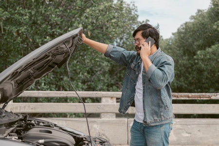 Man driver is using a mobile phone to call for help after car breakdown.の写真素材