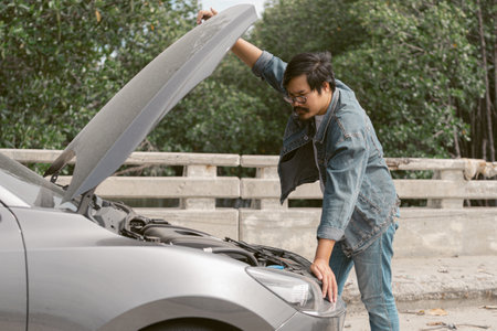 Asian male is checking inside car bonnet after car breakdown. Man driver is trying to repair a car...