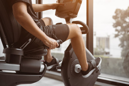 Close up healthy male is riding a spin bike in gym. Fitness man is doing cardio exercise on cycling bikes.の写真素材
