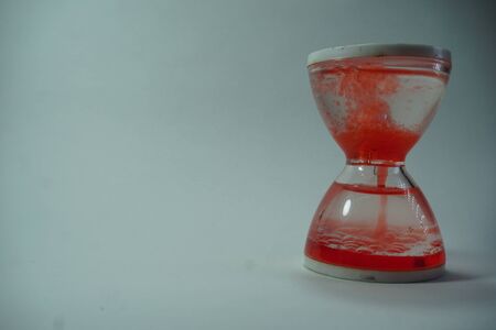 sand clock filled with red liquid in white background