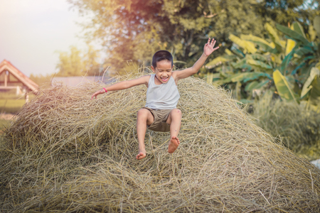 Happy Children wearing a white shirt is playing on straw.の写真素材