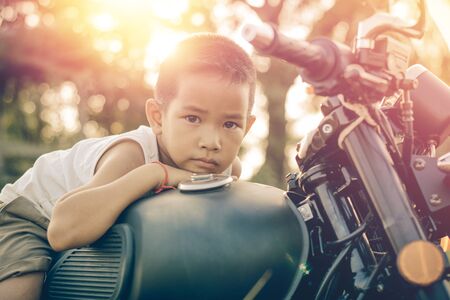 Little kid  on classic motocycle in park.の写真素材
