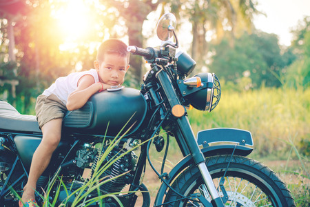 Little kid  on classic motocycle in park.の写真素材