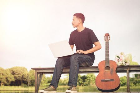 Handsome young men musician sitting prepare work presentations in the park.の写真素材