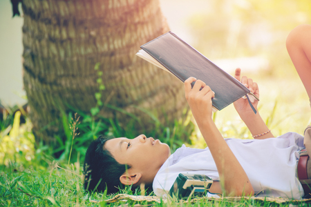 Students reads interesting book on the green grass in the summer park.の写真素材