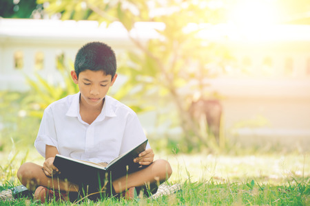 Students reads interesting book on the green grass in the summer park.の写真素材
