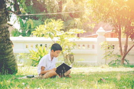 Students reads interesting book on the green grass in the summer park.の写真素材