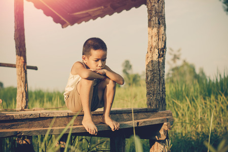 Little boy unhappy sitting alone on abandoned temporary housing.の写真素材