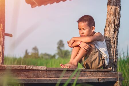 Little boy unhappy sitting alone on abandoned temporary housing.の写真素材